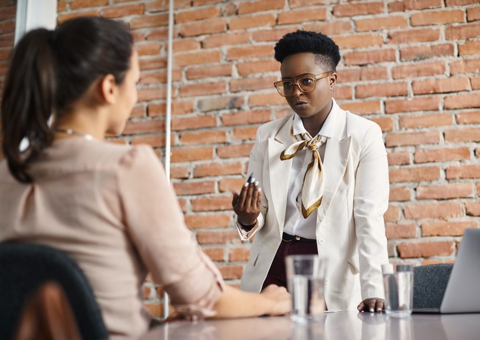 Black female executive talking to female colleague during a meeting in the office.