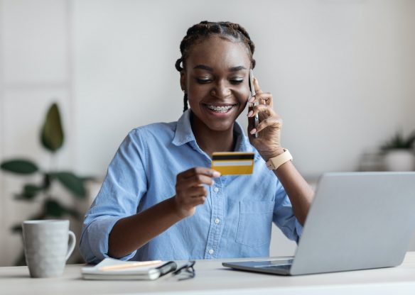 Mobile Payments. Businesswoman Holding Credit Card And Talking On Cellphone In Office