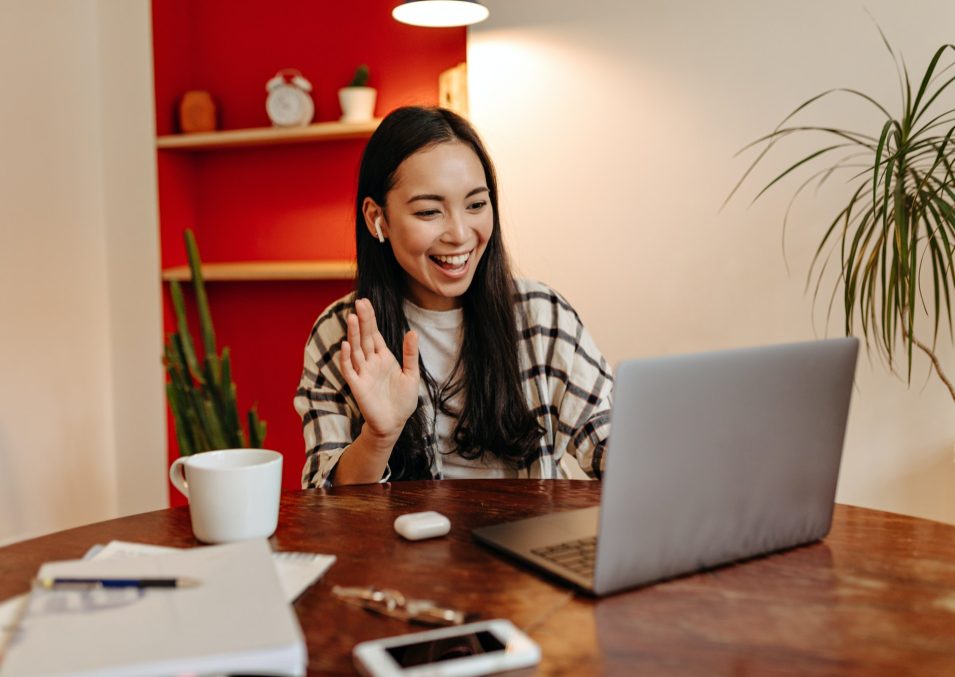 Positive girl in wireless headphones speaks by video link in laptop